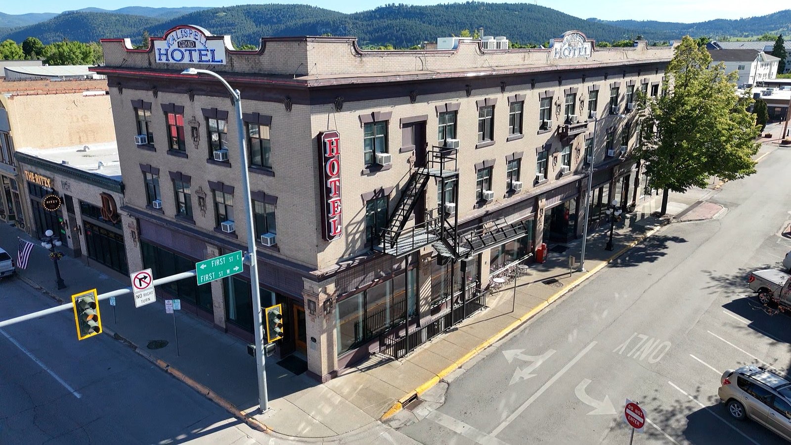 Kalispell Grand Hotel — corner facade with rooftop and vertical neon signage, mountains beyond